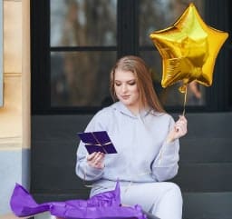 Młoda kobieta ze złotym balonem i prezentem 