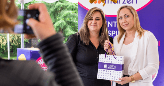 Dwie uśmiechniete młode kobiety z torebką z logo Katalogu Marzeń podczas finału konkursu dla firm